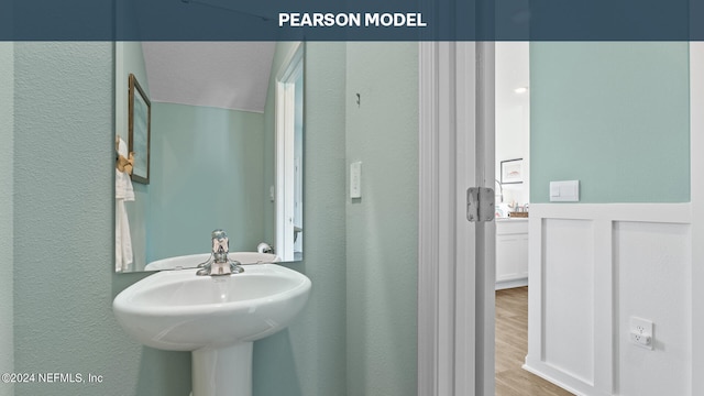 bathroom with a textured wall, wood finished floors, and a sink