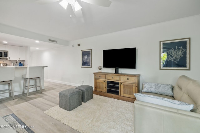 living room featuring light hardwood / wood-style flooring and ceiling fan