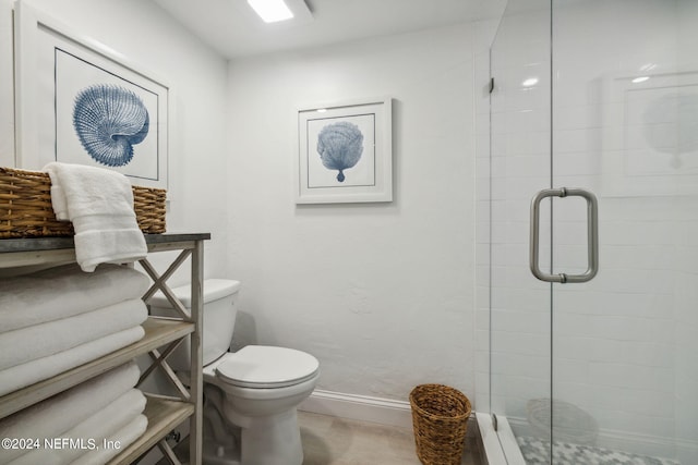 bathroom featuring a shower with door and toilet