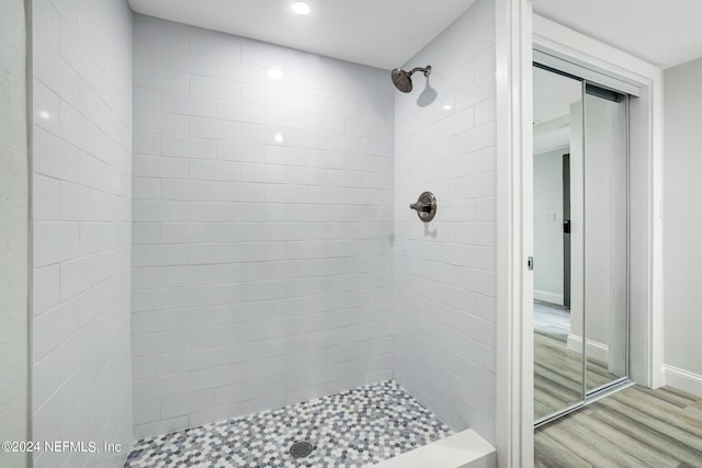 bathroom with tiled shower and hardwood / wood-style floors