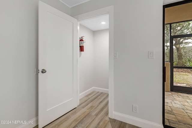 hallway featuring a wealth of natural light, crown molding, and light hardwood / wood-style flooring