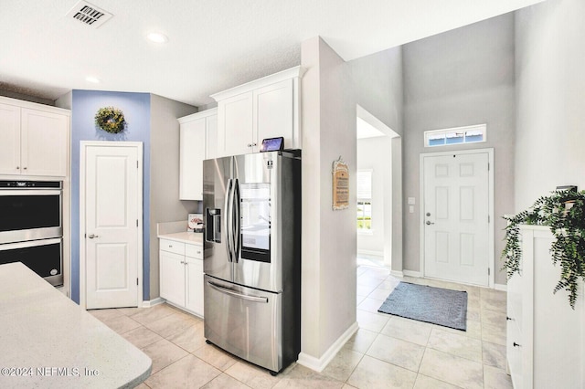 kitchen with light tile patterned floors, stainless steel appliances, and white cabinetry