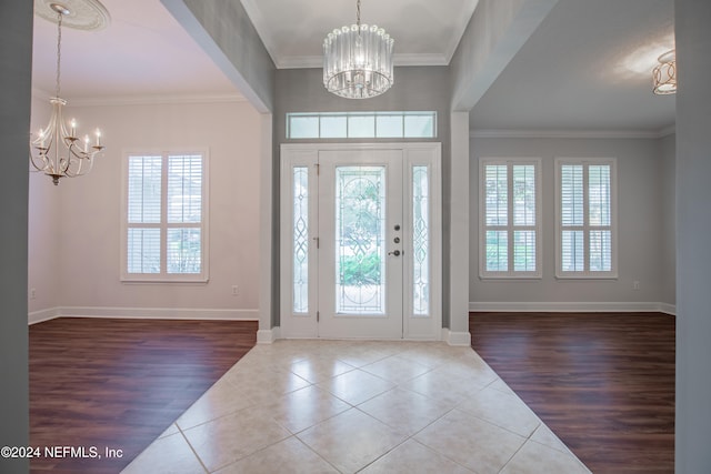 tiled entrance foyer featuring ornamental molding and a notable chandelier