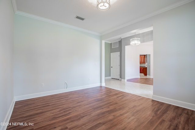 unfurnished room with crown molding, hardwood / wood-style floors, and a notable chandelier