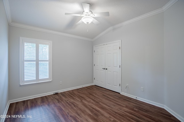 unfurnished bedroom with dark hardwood / wood-style floors, lofted ceiling, ceiling fan, crown molding, and a closet