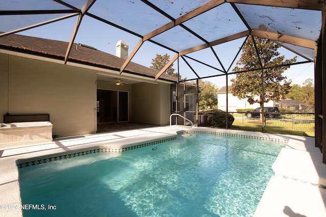 view of swimming pool featuring ceiling fan, a lanai, and a patio