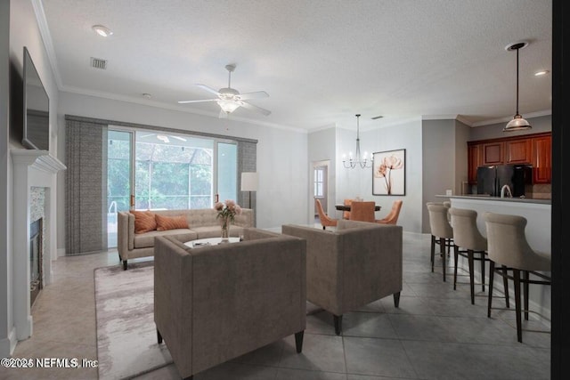 tiled living room featuring ceiling fan with notable chandelier, ornamental molding, and a textured ceiling