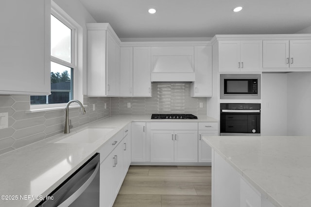 kitchen featuring white cabinetry, light stone countertops, custom exhaust hood, and black appliances