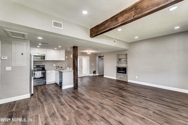 kitchen featuring beamed ceiling, white cabinets, stainless steel appliances, and a textured ceiling