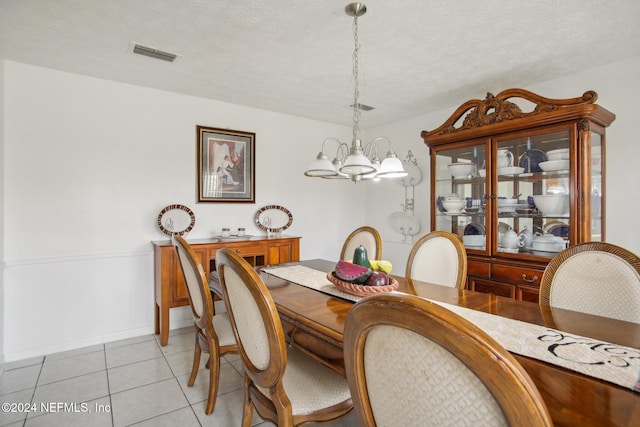 tiled dining space with a textured ceiling and an inviting chandelier