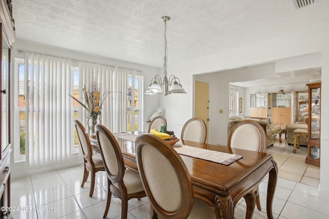 tiled dining room with a notable chandelier and a textured ceiling