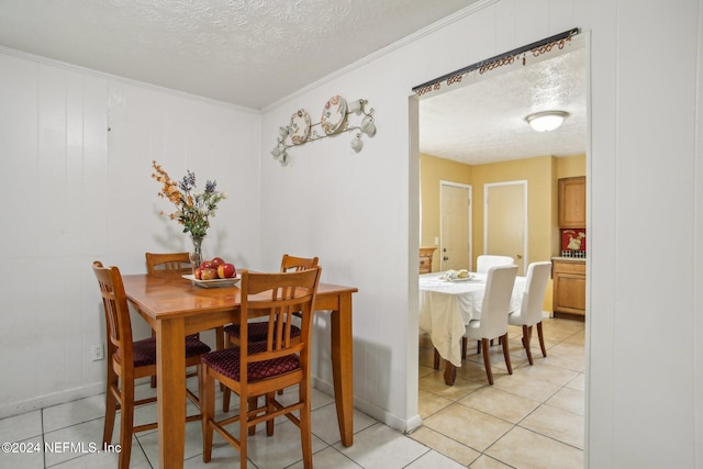 dining space with light tile patterned flooring, ornamental molding, and a textured ceiling