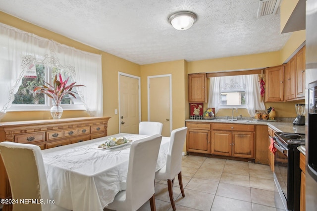 dining space featuring sink, light tile patterned floors, and a textured ceiling