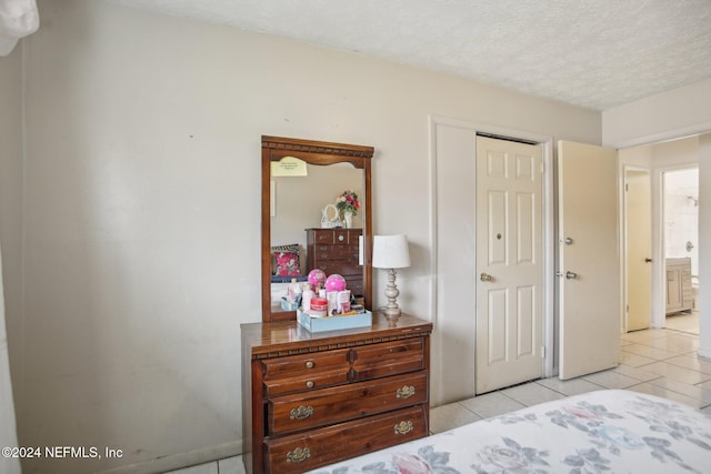 bedroom featuring light tile patterned floors and a textured ceiling