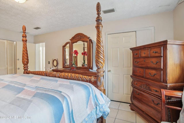 tiled bedroom with a textured ceiling and a closet