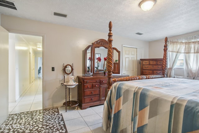 bedroom featuring light tile patterned floors, a textured ceiling, and a closet