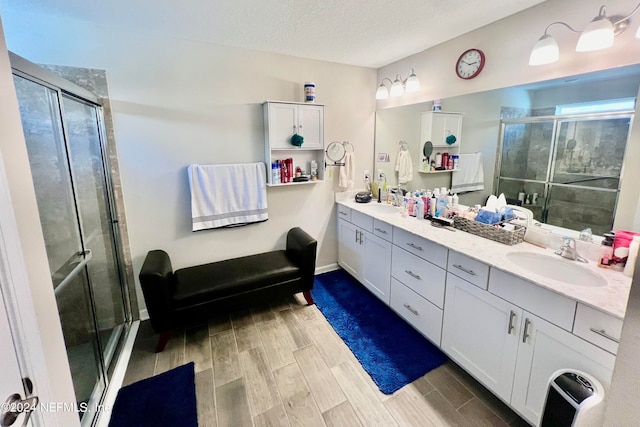 bathroom featuring vanity, an enclosed shower, a textured ceiling, and hardwood / wood-style flooring