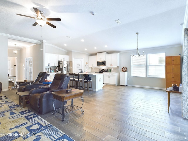 living area featuring light wood finished floors, baseboards, lofted ceiling, ornamental molding, and ceiling fan with notable chandelier