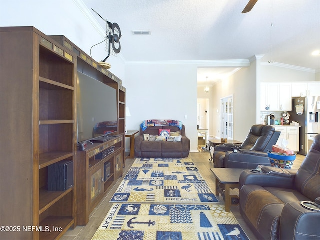 living room with crown molding, visible vents, light wood-style floors, vaulted ceiling, and ceiling fan