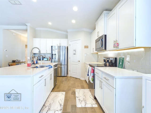 kitchen featuring stainless steel appliances, visible vents, white cabinets, light countertops, and ornamental molding