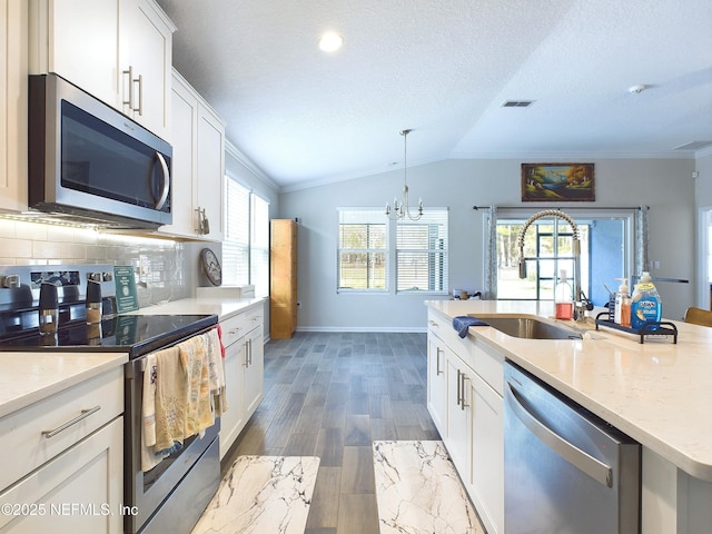 kitchen featuring stainless steel appliances, visible vents, white cabinets, vaulted ceiling, and tasteful backsplash