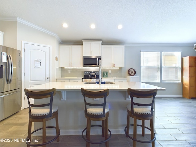 kitchen with appliances with stainless steel finishes, light countertops, a kitchen island with sink, and backsplash