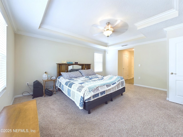 carpeted bedroom featuring baseboards, visible vents, a ceiling fan, ornamental molding, and a tray ceiling