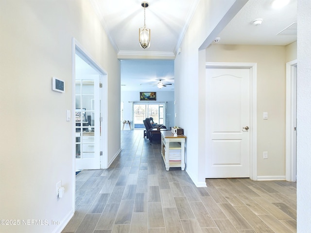 corridor featuring baseboards, crown molding, and light wood finished floors