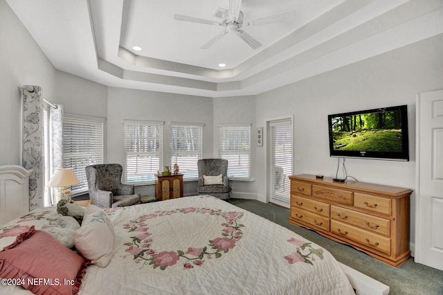 carpeted bedroom with ceiling fan and a raised ceiling