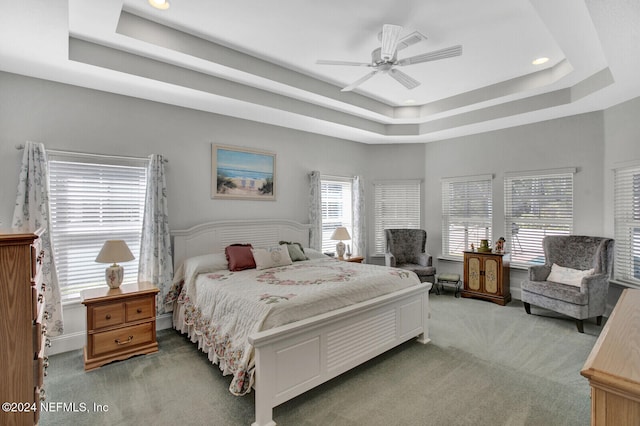 carpeted bedroom with ceiling fan and a raised ceiling