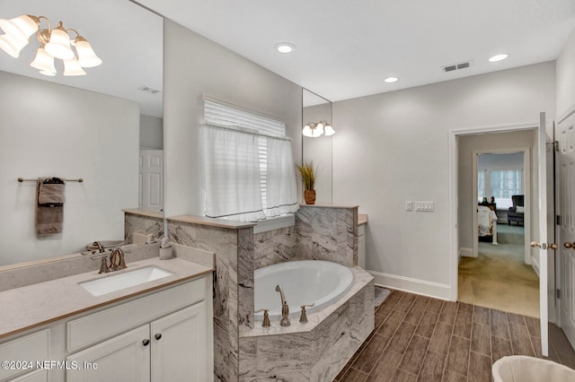 bathroom with vanity, wood-type flooring, and tiled tub