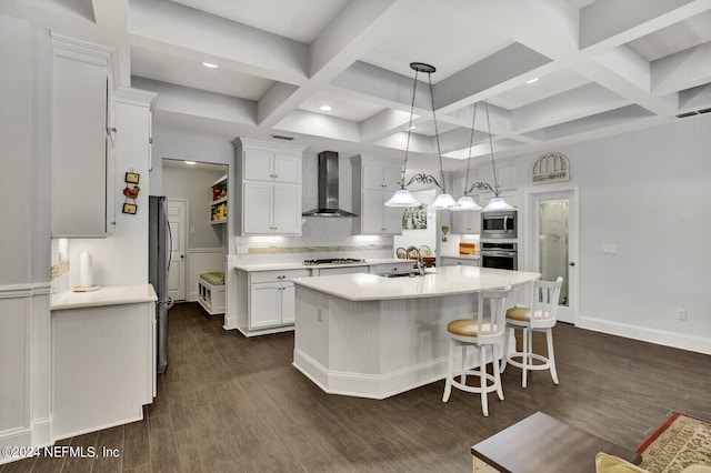 kitchen with wall chimney exhaust hood, dark wood-type flooring, white cabinets, and stainless steel appliances