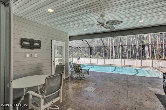 view of swimming pool featuring ceiling fan, glass enclosure, and a patio area