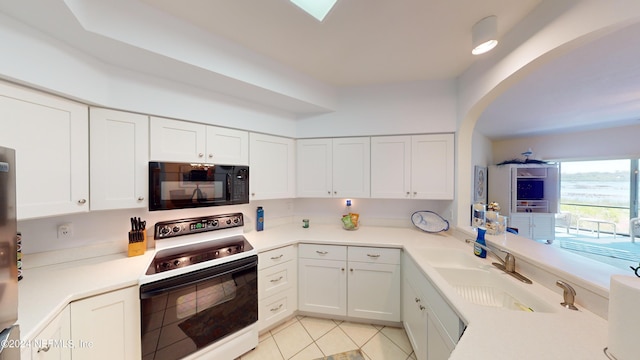 kitchen featuring a sink, range with electric stovetop, black microwave, and white cabinetry