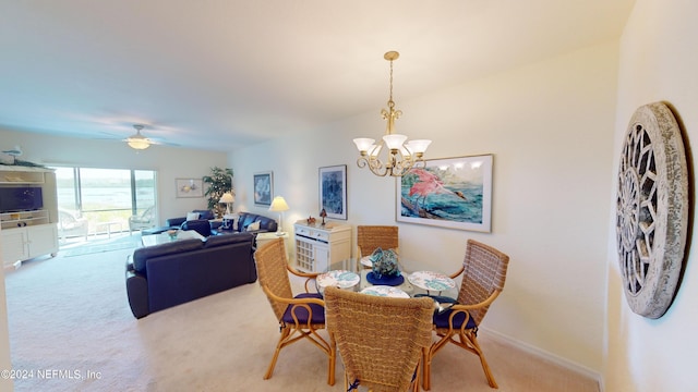 carpeted dining area with ceiling fan with notable chandelier and baseboards