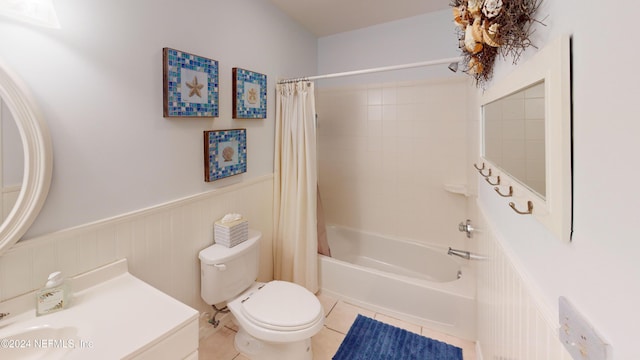 bathroom featuring shower / bathtub combination with curtain, toilet, wainscoting, tile patterned flooring, and vanity