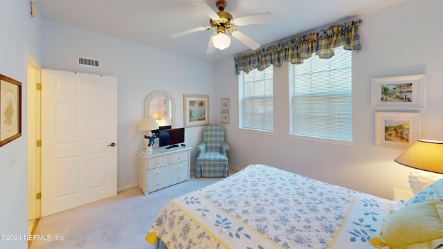 carpeted bedroom featuring a ceiling fan, visible vents, and baseboards