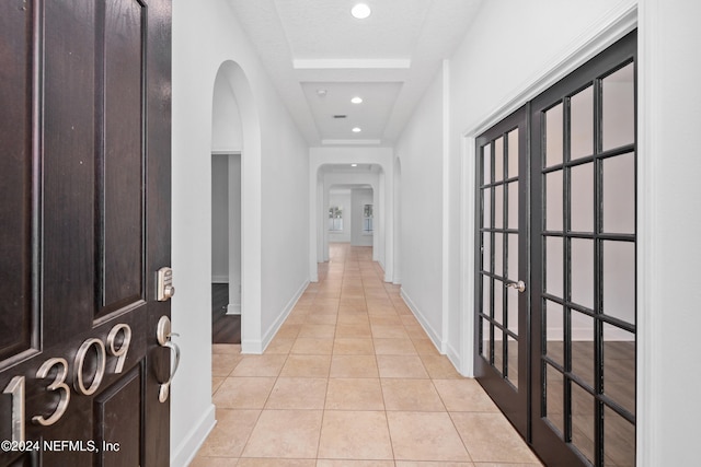 corridor featuring light tile patterned floors and a textured ceiling