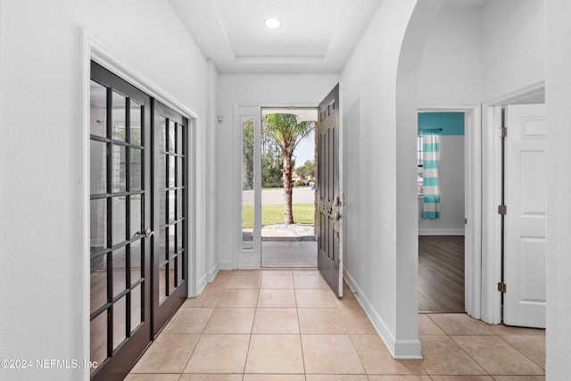 doorway to outside with a textured ceiling, plenty of natural light, light tile patterned floors, and french doors