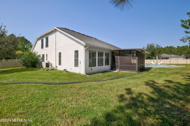 back of property featuring a yard, a fenced in pool, and a sunroom