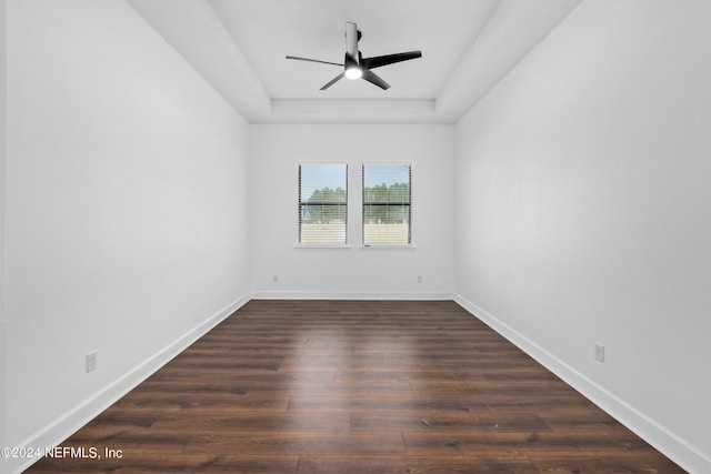 unfurnished room featuring dark hardwood / wood-style floors, ceiling fan, and a tray ceiling