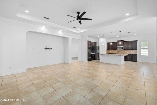 unfurnished living room with ceiling fan, a raised ceiling, light tile patterned floors, and sink