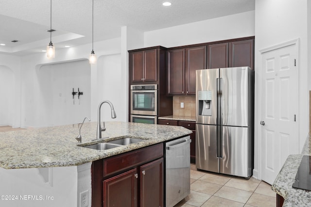 kitchen with sink, light tile patterned floors, a textured ceiling, light stone counters, and stainless steel appliances