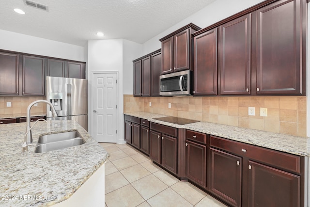 kitchen with light stone countertops, appliances with stainless steel finishes, decorative backsplash, a textured ceiling, and sink