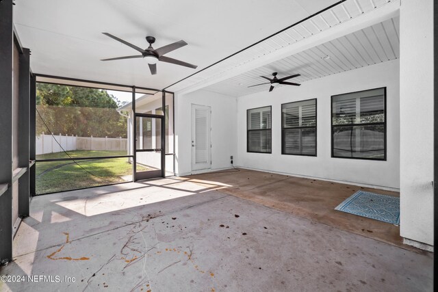 unfurnished sunroom with ceiling fan and beam ceiling