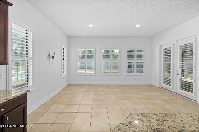 interior space with light tile patterned floors and a textured ceiling