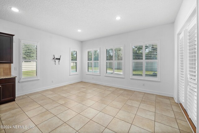 unfurnished room with light tile patterned floors and a textured ceiling