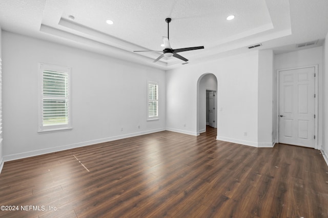 unfurnished room featuring plenty of natural light, dark wood-type flooring, and a tray ceiling