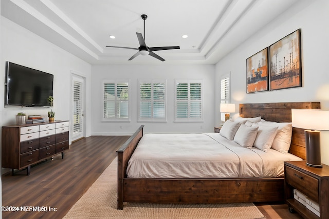 bedroom with a raised ceiling, ceiling fan, wood-type flooring, and access to outside