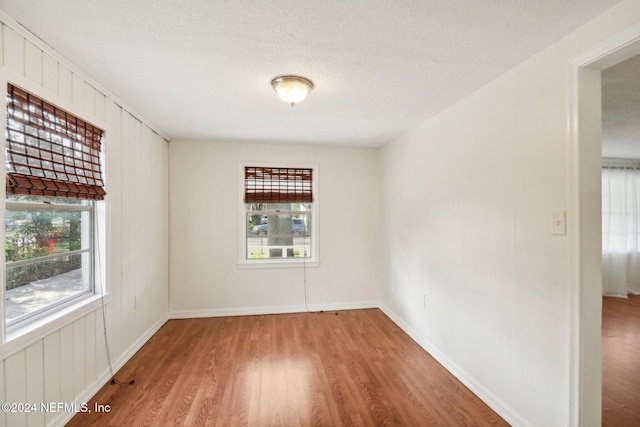 spare room featuring hardwood / wood-style flooring, a textured ceiling, and a healthy amount of sunlight